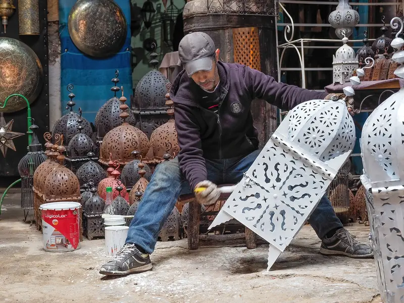 An artisan crafting a metal lantern in the Marrakech medina
